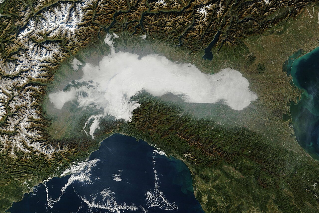 Niebla acumulada en un valle de tierras bajas (Llanura Pádica) — signo típico de retención de aire frío