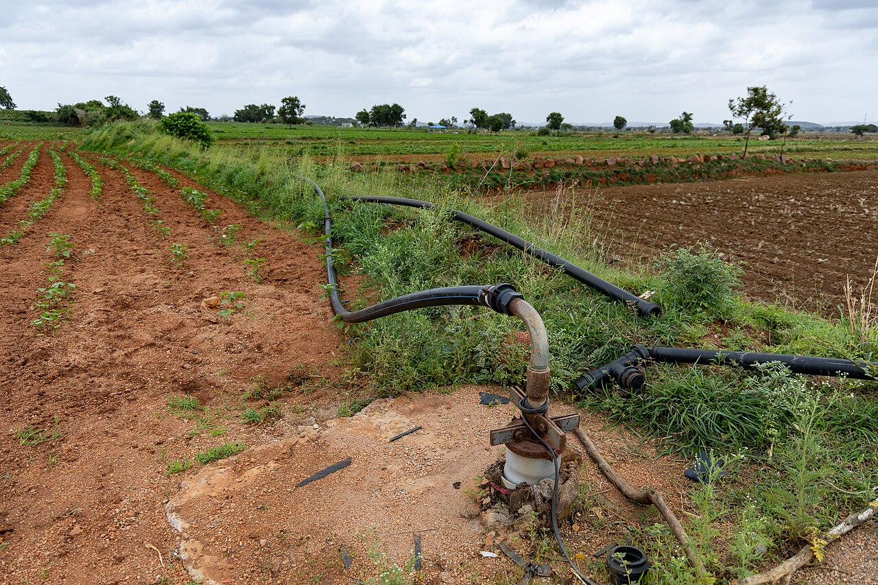 Bomba en un pozo perforado (pozo artesiano) con distribución de tuberías para riego en una parcela agrícola