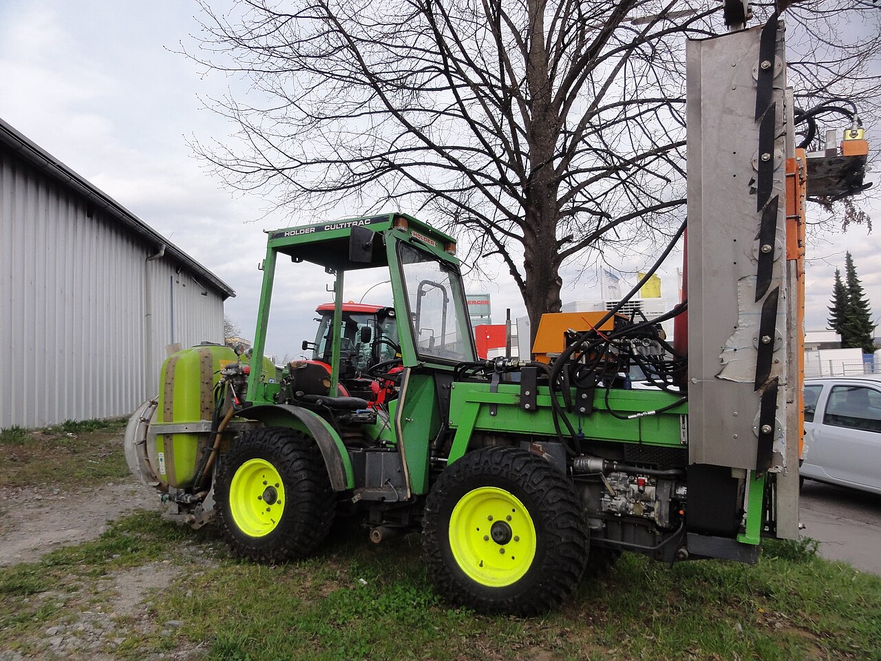 Tractor para plantaciones equipado con tanque de pulverización y accesorio para el tratamiento de hileras